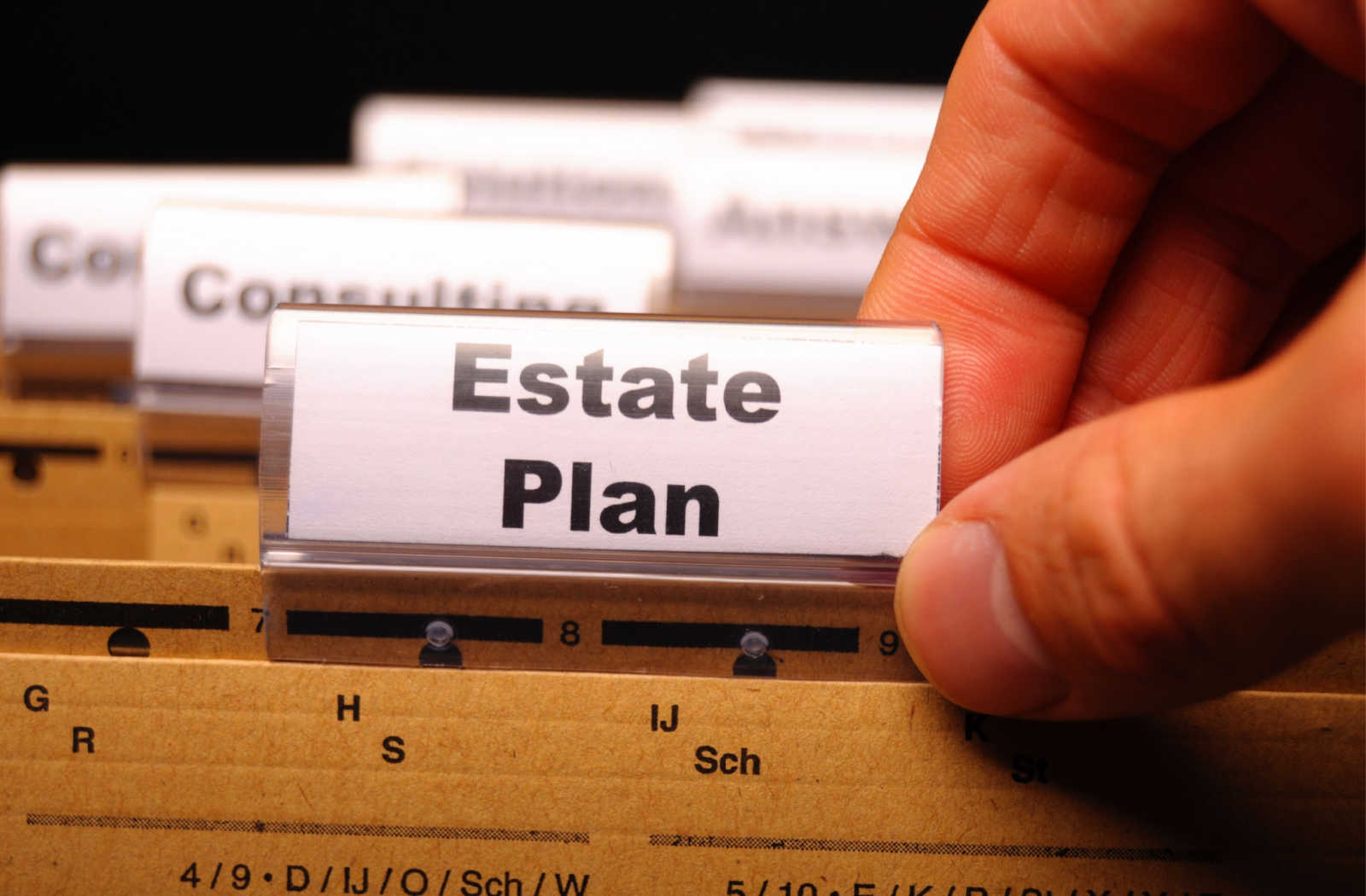 A close up of a hand reaching for a file folder labelled estate planning