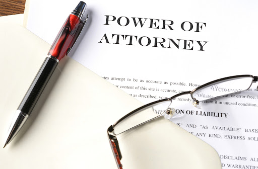 A power of attorney document laying on a desk with a pen and pair of glasses sitting on top