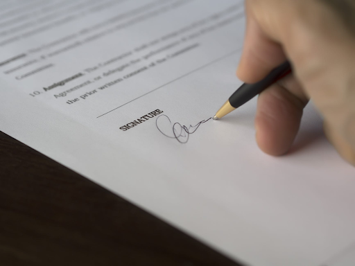 A hand signing the bottom of a will when estate planning