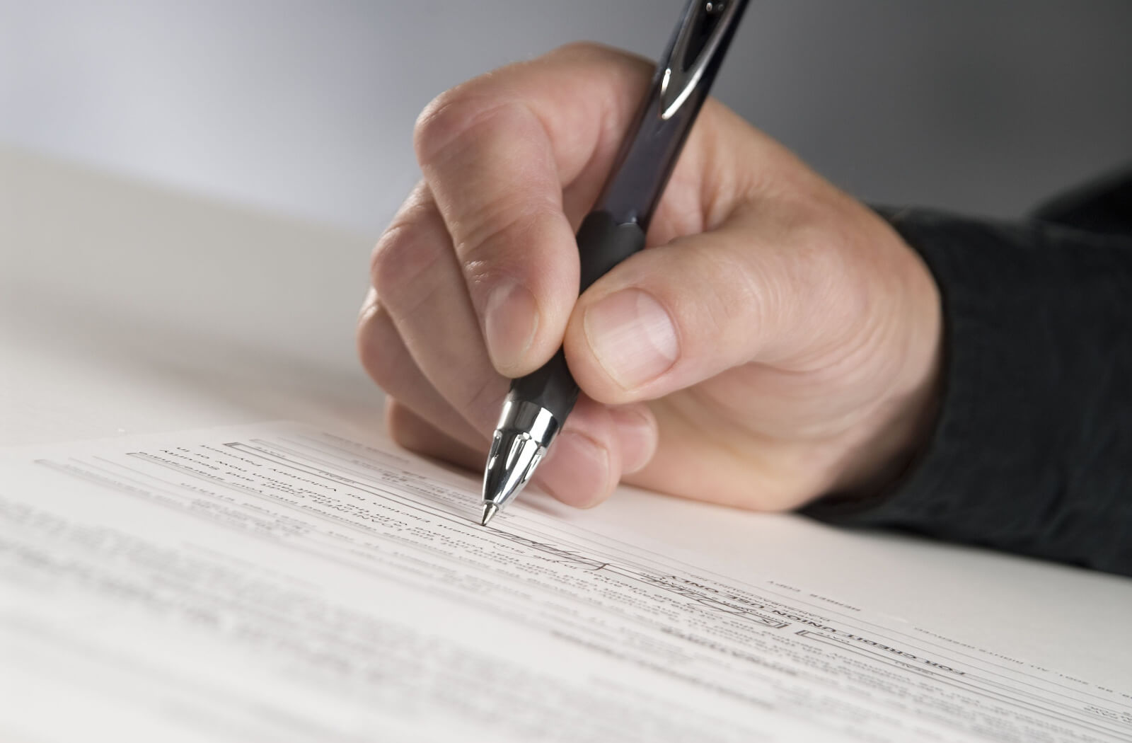 Close-up of a hand holding pen and filling out a form