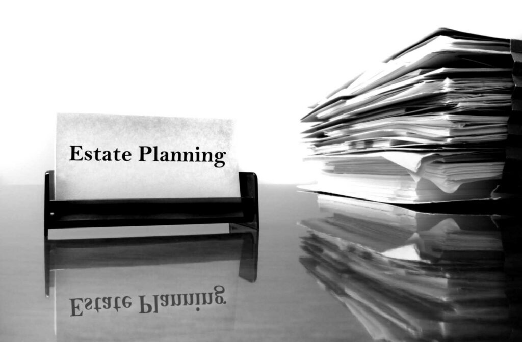 A stack of papers on a desk next to a sign that says estate planning